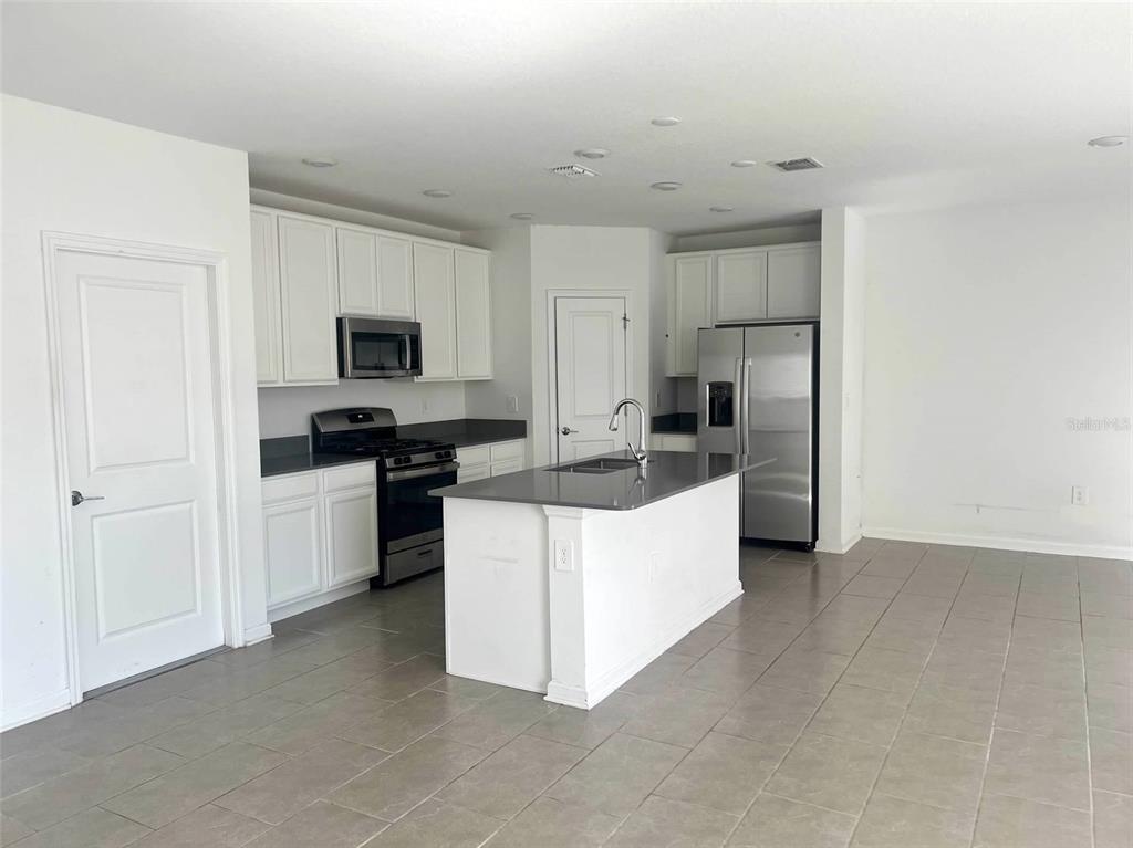 5554 Braken Fern Way Leesburg, FL 34748 - Photo 3 of 16 a large kitchen with cabinets and stainless steel appliances