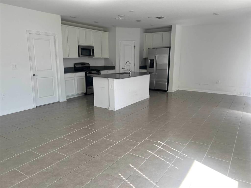 5554 Braken Fern Way Leesburg, FL 34748 - Photo 4 of 16 a kitchen with stainless steel appliances a sink a stove a microwave a sink a refrigerator and cabinets