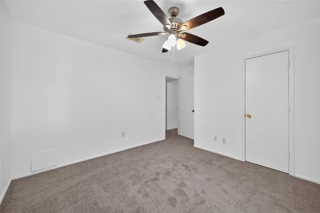 an empty room with a ceiling fan and a window
