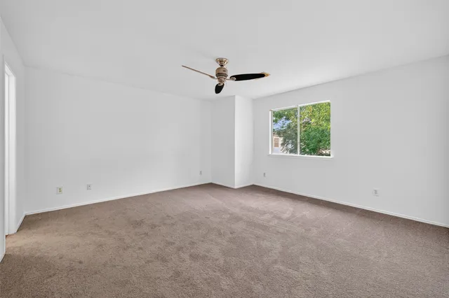 an empty room with a window and a ceiling fan
