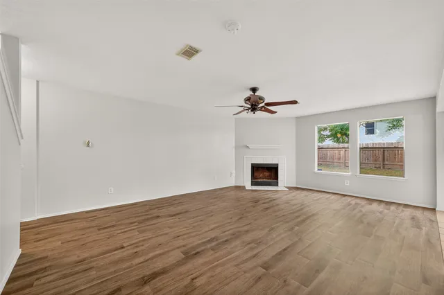 a view of empty room with fireplace and wooden floor