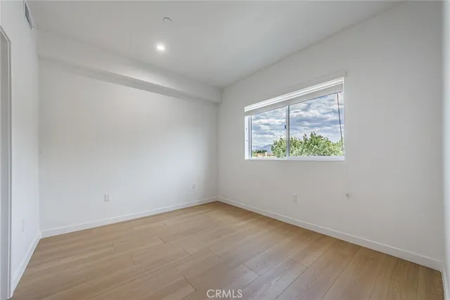 an empty room with wooden floor and window