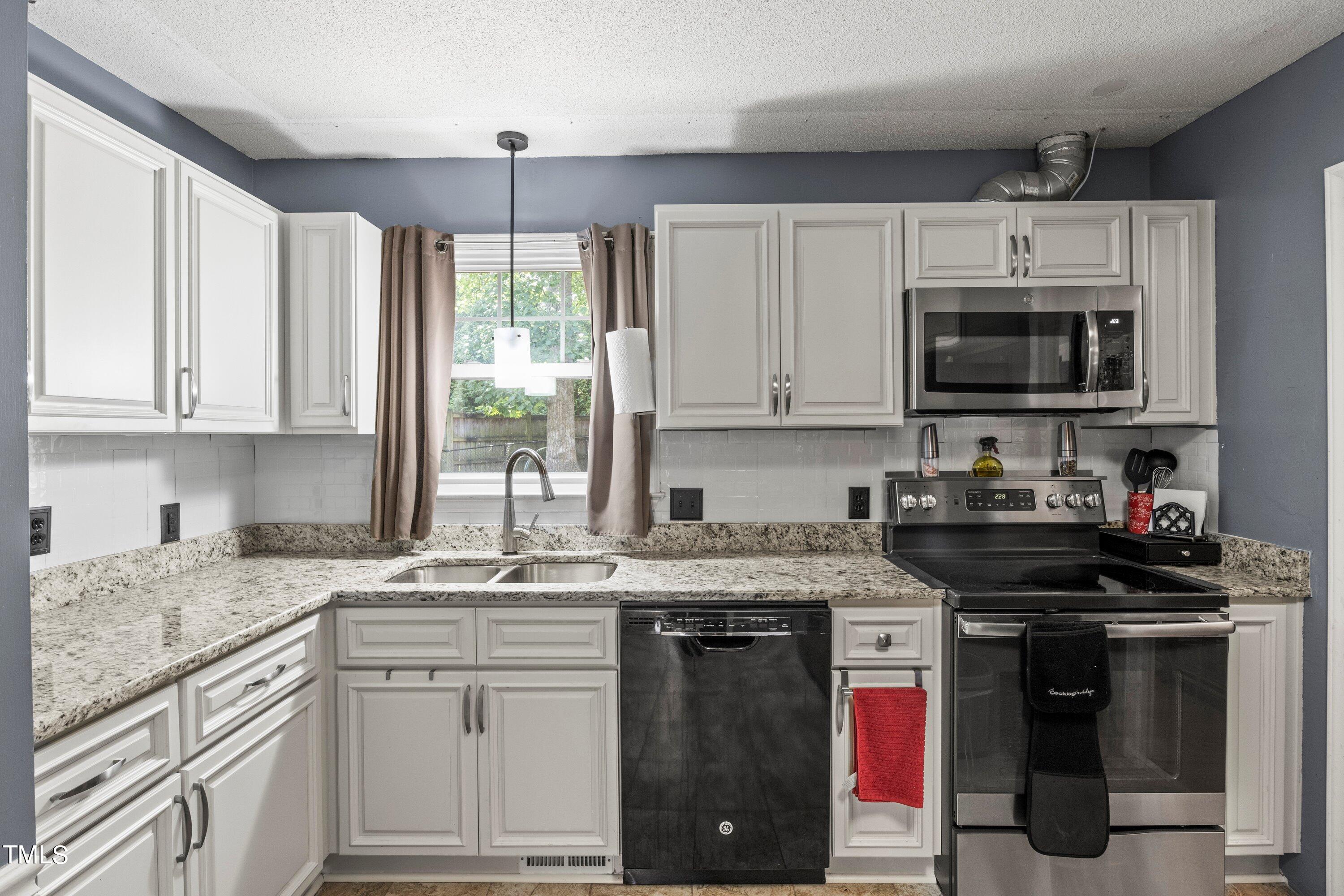 4125 Windsor Place Raleigh, NC 27609 - Photo 17 of 37 a kitchen with stainless steel appliances granite countertop a stove a sink and a microwave