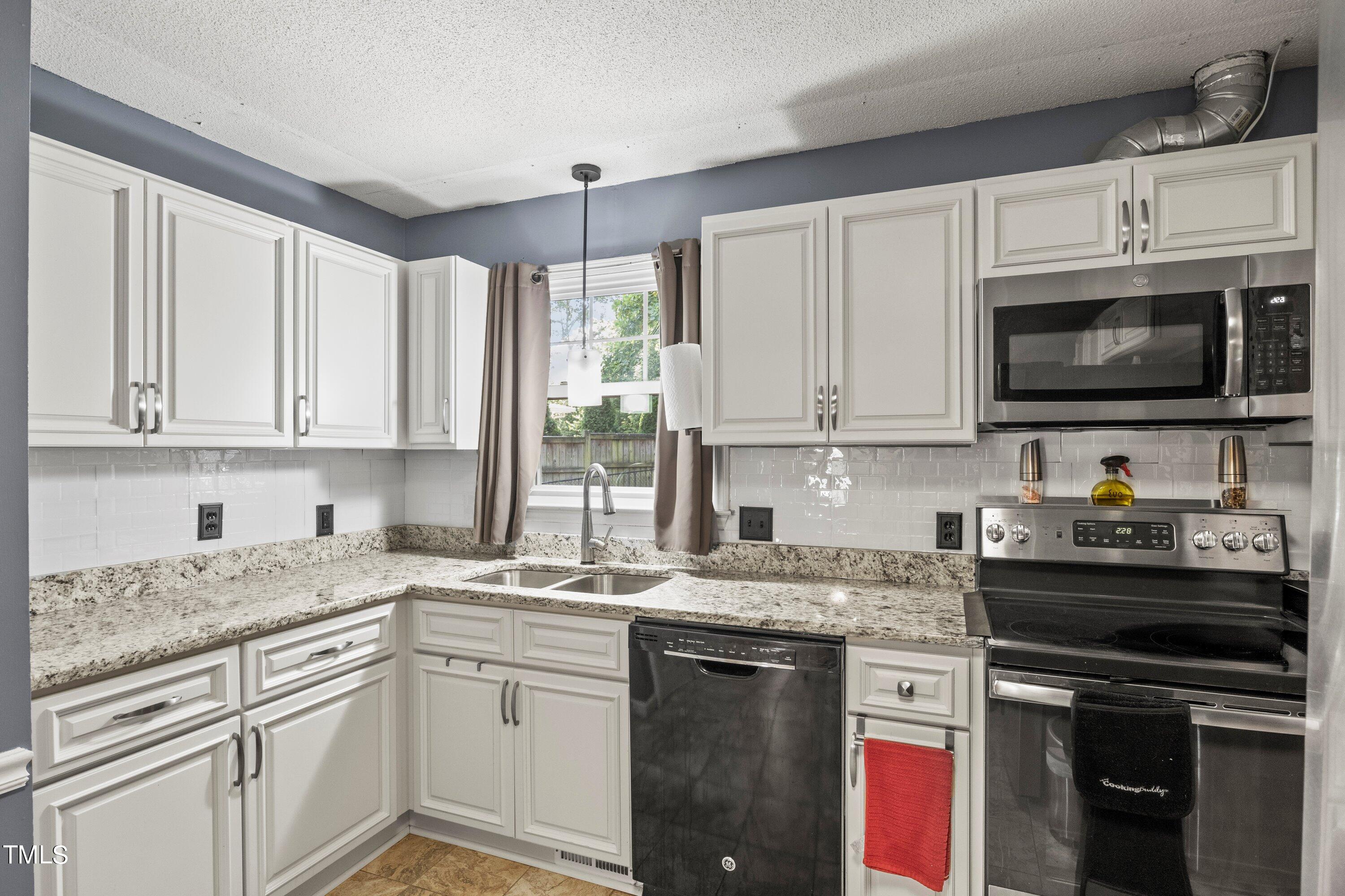 4125 Windsor Place Raleigh, NC 27609 - Photo 18 of 37 a kitchen with granite countertop white cabinets sink and stainless steel appliances