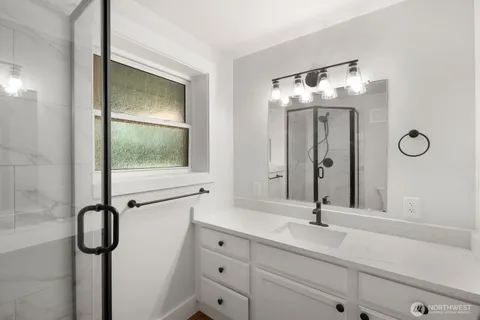 a bathroom with a double vanity sink mirror and shower