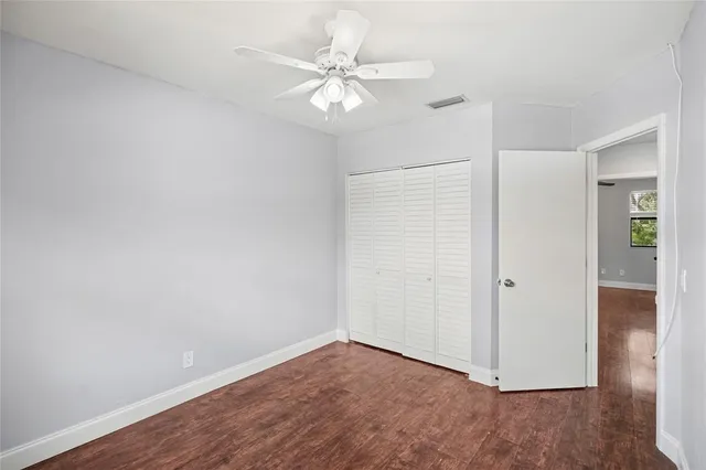 an empty room with wooden floor and ceiling fan