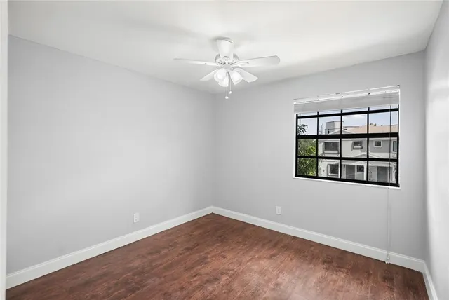 an empty room with a window and ceiling fan