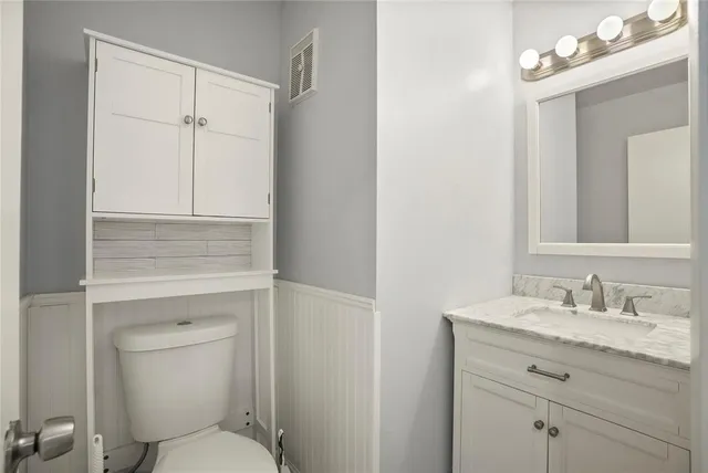a bathroom with a toilet sink vanity and granite