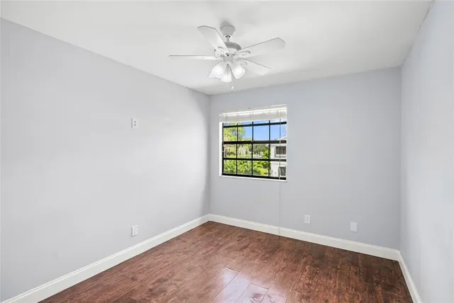 an empty room with windows and ceiling fan