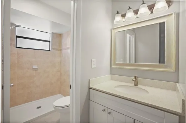 a bathroom with a granite countertop sink a toilet and shower
