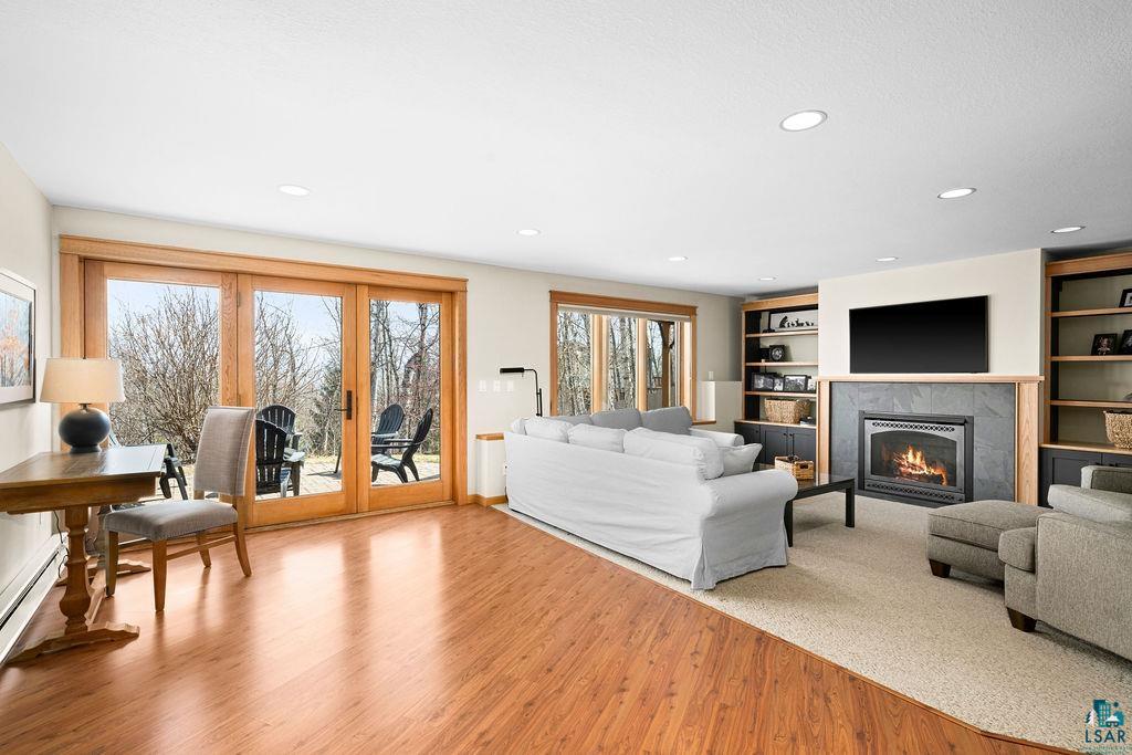 4856 Kingston Street Duluth, MN 55804 - Photo 40 of 88 Spacious living area featuring wood-finish flooring, a built-in fireplace with a stone surround and wood mantle, recessed lighting, and built-in shelving units