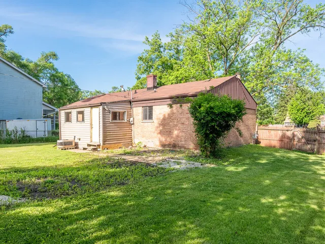 a backyard of a house with table and chairs and potted plants