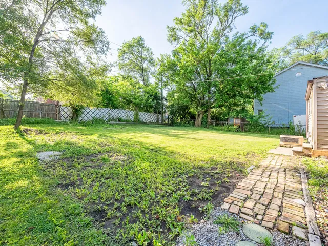a view of a swimming pool with a yard and large trees