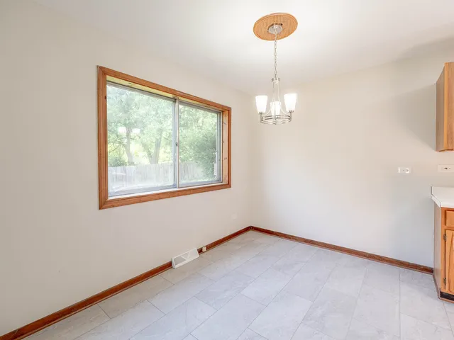 an empty room with windows and chandelier fan