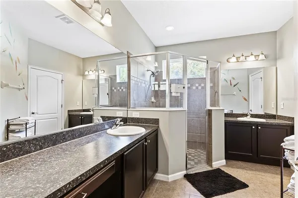 a bathroom with a granite countertop sink a large mirror and a shower