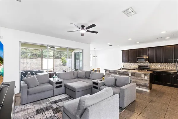 a living room with furniture kitchen area and a large window