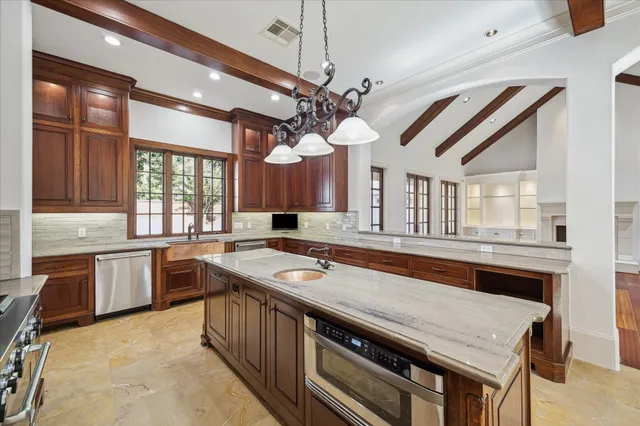 a kitchen with a stove a sink dishwasher a dining table and chairs with wooden floor