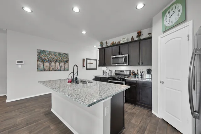 a kitchen with stainless steel appliances granite countertop a refrigerator a stove top oven a sink and dishwasher