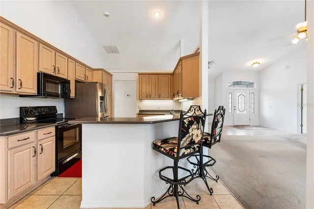 a kitchen with stainless steel appliances kitchen island granite countertop a table chairs microwave and sink