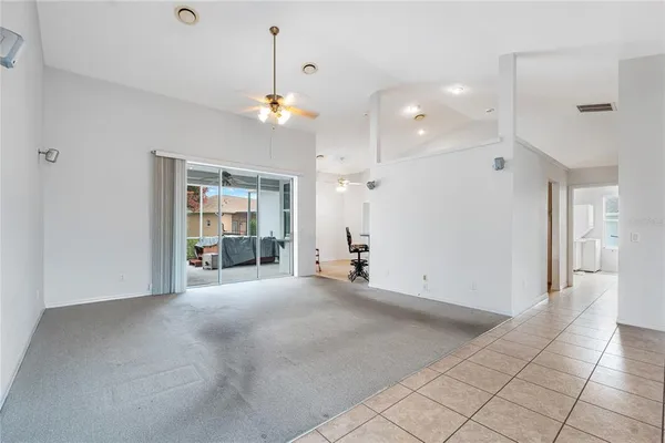 a view of an empty room with kitchen and a window