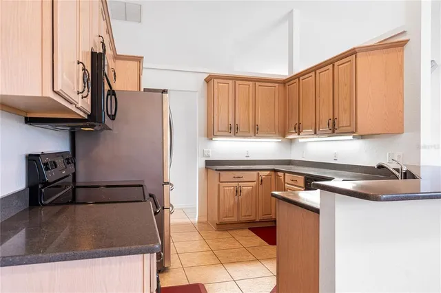 a kitchen with stainless steel appliances granite countertop a refrigerator a stove and a sink with wooden cabinets