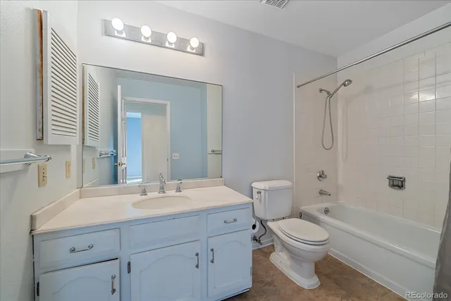 a bathroom with a toilet a sink a mirror a bathtub and vanity
