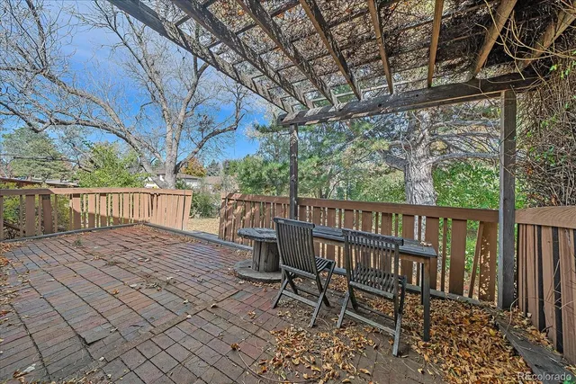 a view of a wooden deck with chairs and large trees