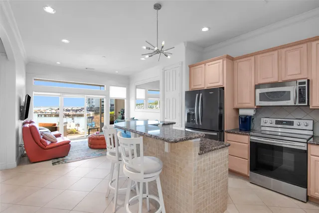 a kitchen with stainless steel appliances kitchen island granite countertop a stove a sink dishwasher a dining table and chairs with the kitchen view