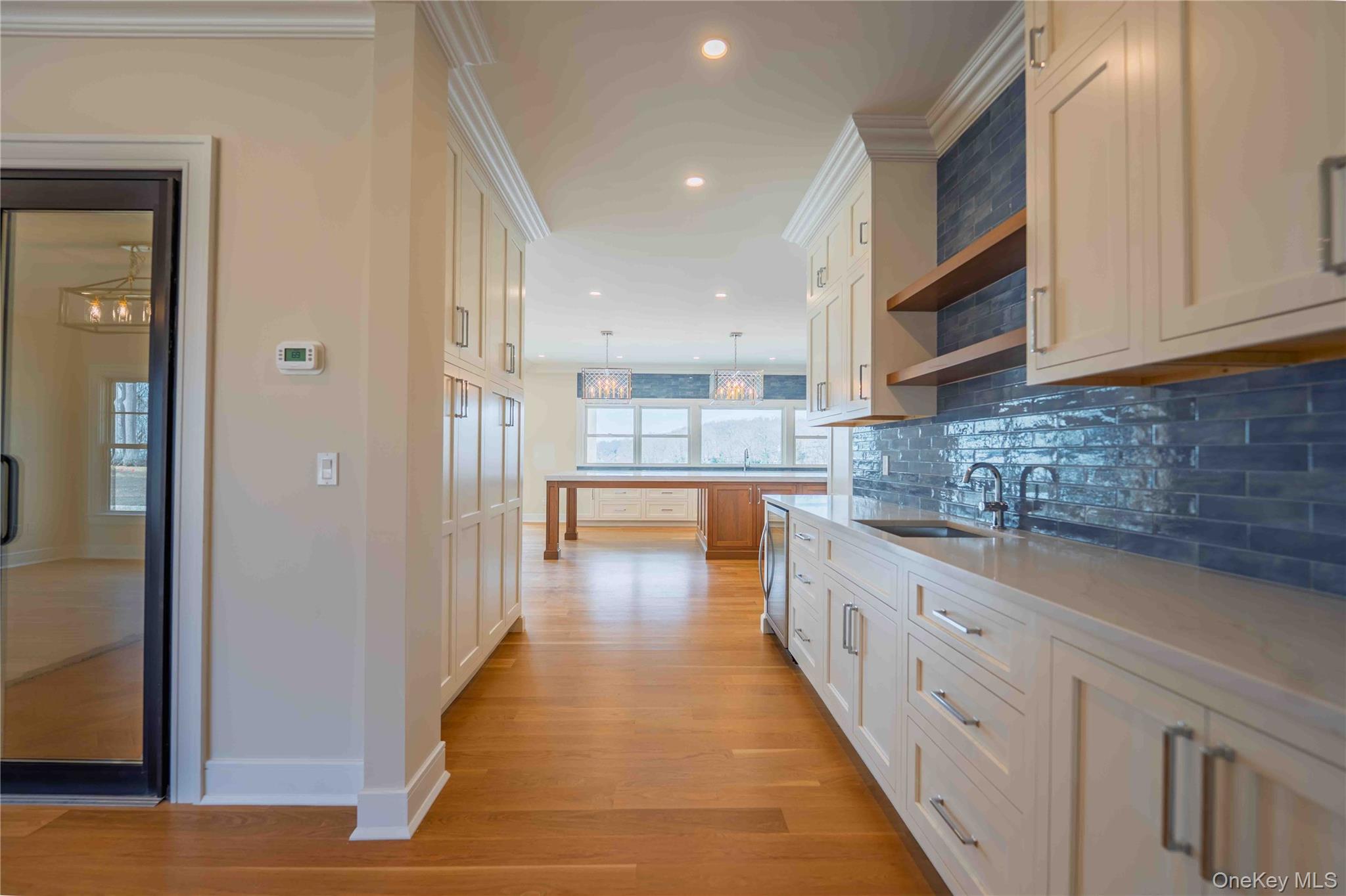 106 Cove Road Asharoken, NY 11768 - Photo 11 of 46 Two tone kitchen featuring ornamental molding, open shelves, decorative light fixtures, decorative backsplash, and light wood-style floors