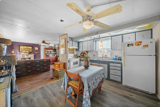 a kitchen with a refrigerator a stove top oven a dining table and chairs