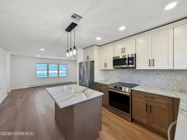 a kitchen with stainless steel appliances kitchen island granite countertop a stove a sink and a refrigerator