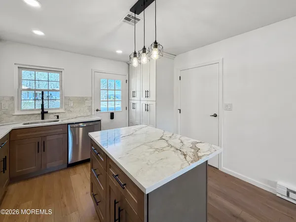 a kitchen with a stove a sink a center island and wooden floor