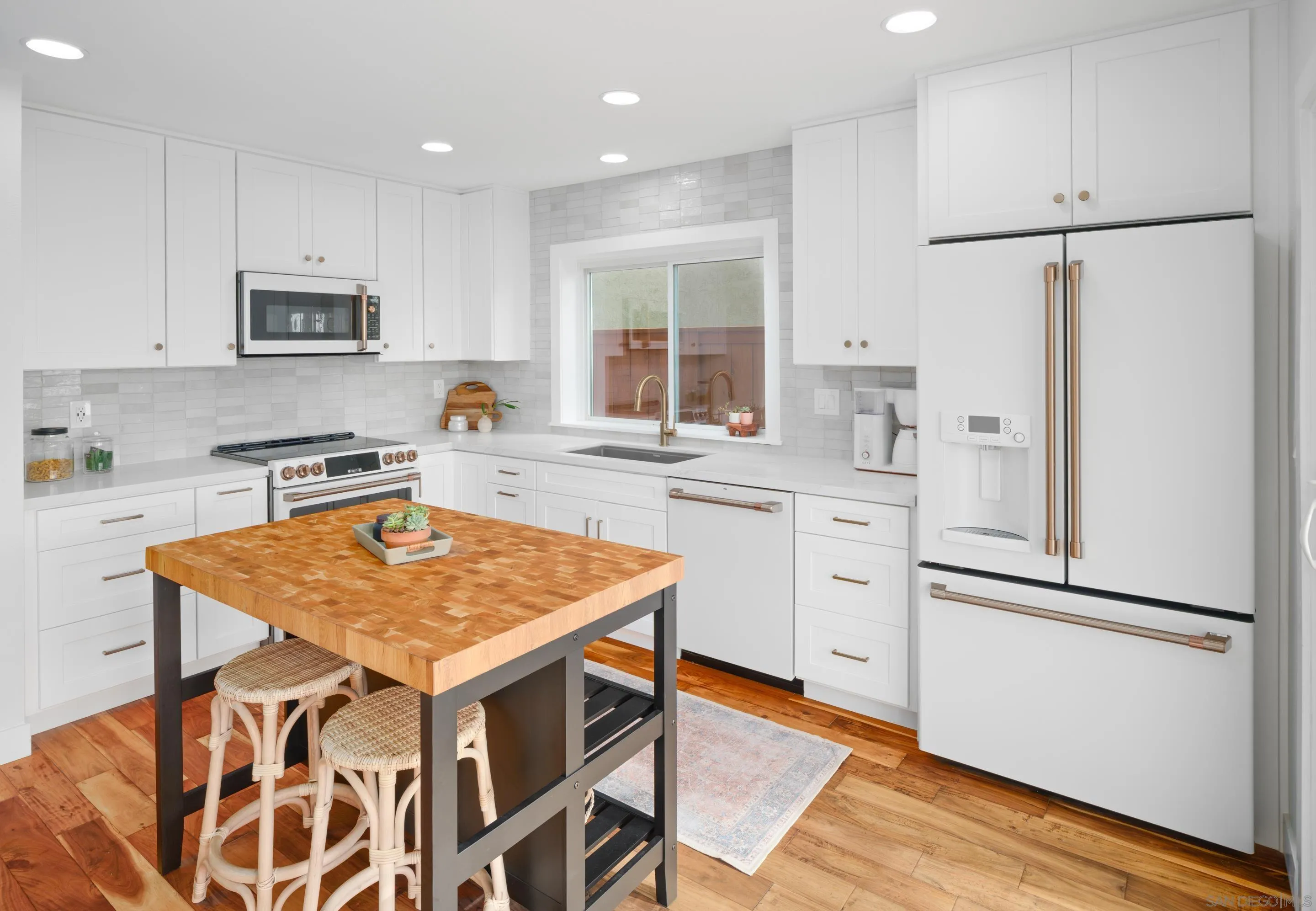 7053 Snapdragon Drive Carlsbad, CA 92011 - Photo 9 of 35 a kitchen with stainless steel appliances granite countertop a refrigerator a sink dishwasher a stove a dining table and chairs with wooden floor