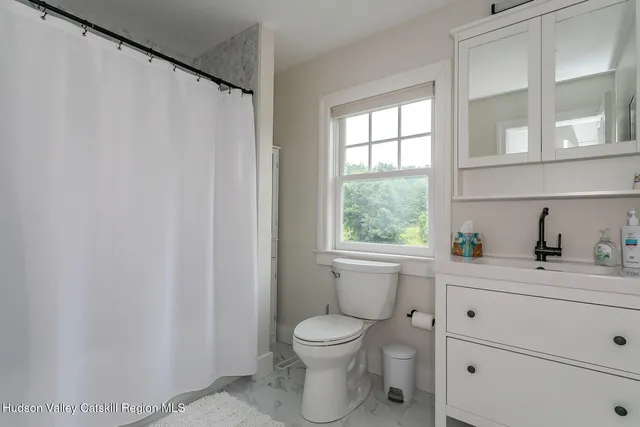 a bathroom with a granite countertop toilet a sink a mirror and a window
