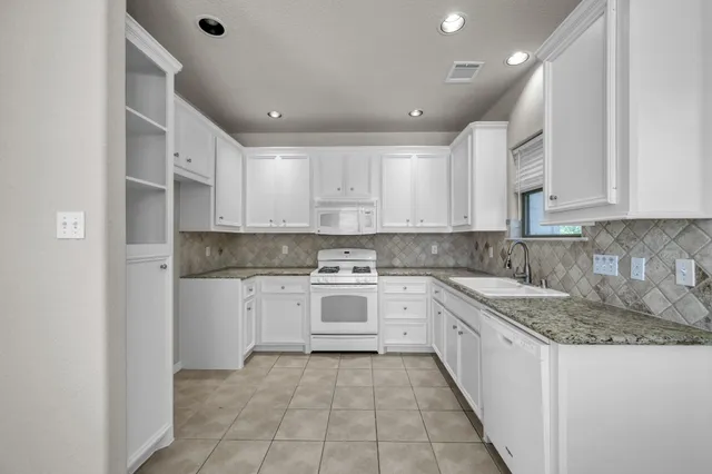 a kitchen that has a lot of white cabinets and stainless steel appliances