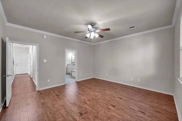 a view of an empty room with chandelier fan and wooden floor