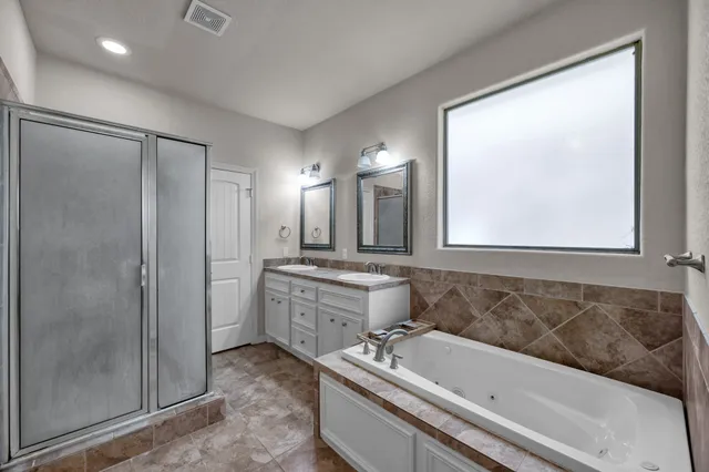 a bathroom with a tub a sink and mirror