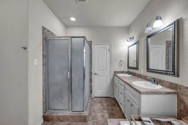 a bathroom with a double vanity sink mirror and shower