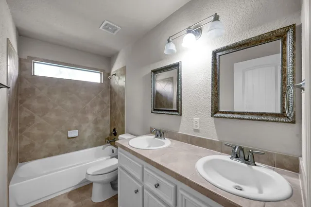 a bathroom with a granite countertop toilet a sink and a mirror