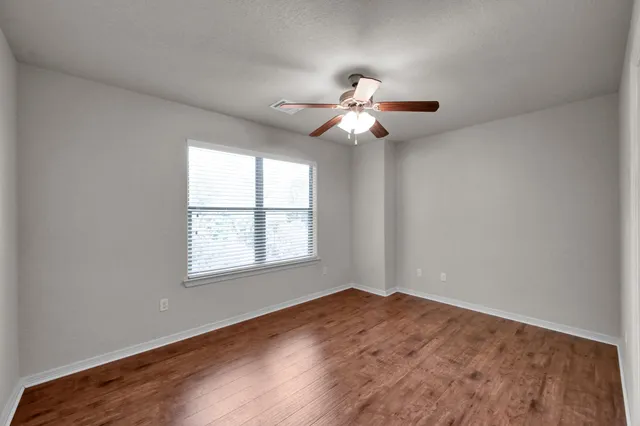 an empty room with a window and a fan