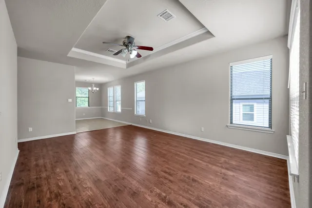 an empty room with wooden floor and windows