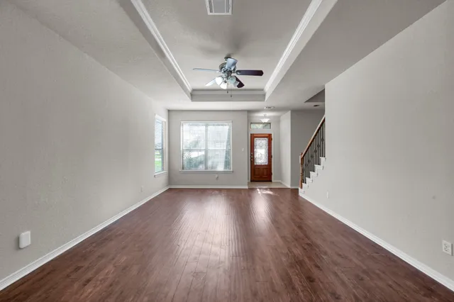 an empty room with wooden floor chandelier and windows