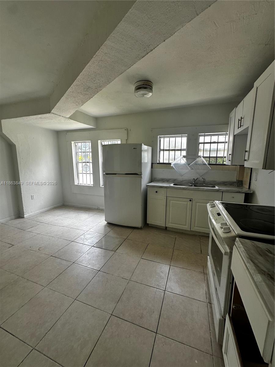 1925 Northwest 56th Street Miami, FL 33142 - Photo 5 of 27 a kitchen with a sink a stove top oven and cabinets
