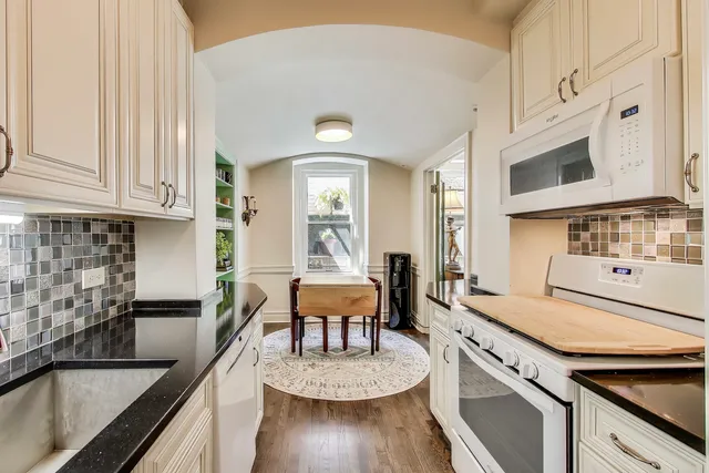 a kitchen with stainless steel appliances granite countertop a stove a sink and a white cabinets