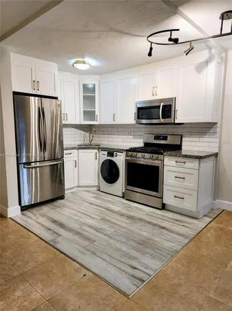 a kitchen with stainless steel appliances granite countertop a stove a refrigerator and a microwave