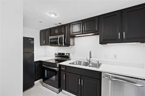 a kitchen with granite countertop a sink cabinets and stainless steel appliances