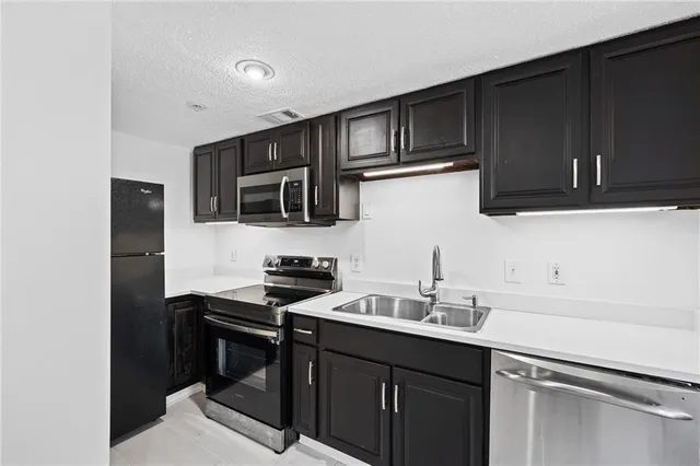 a kitchen with granite countertop a sink cabinets and stainless steel appliances