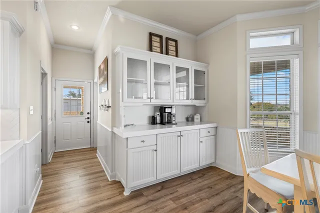 a kitchen with white cabinets and wooden floor
