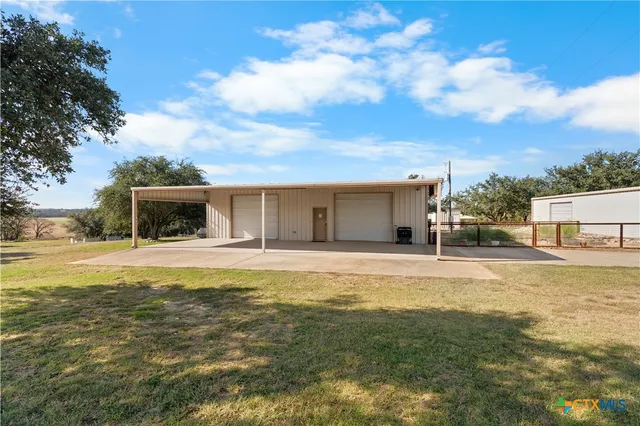 a view of a house with a yard and a large tree