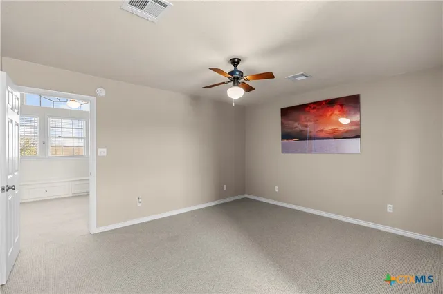 an empty room with a window and a ceiling fan